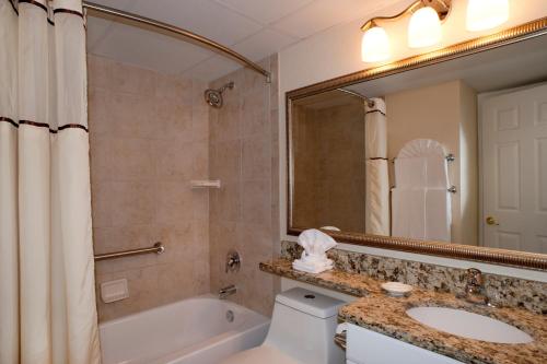 a bathroom with a tub and a toilet and a sink at Casa Del Mar Beachfront Suites in Galveston