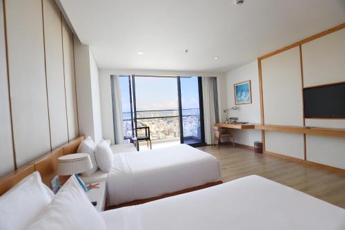 a hotel room with two beds and a flat screen tv at TMS Hotel Da Nang Beach in Da Nang