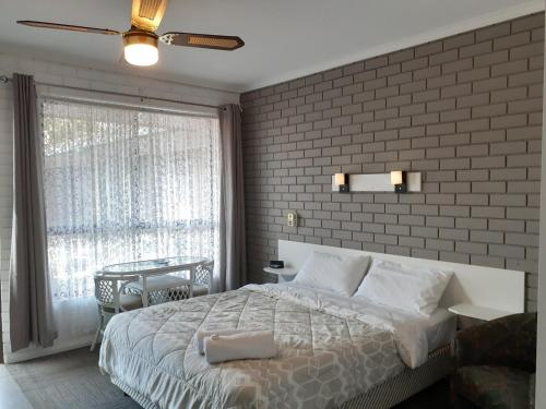 een slaapkamer met een groot bed en een bakstenen muur bij Birch Motel Tocumwal in Tocumwal