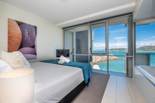 a bedroom with a bed and a view of the ocean at One Bright Point - Stunning Water Views in Nelly Bay