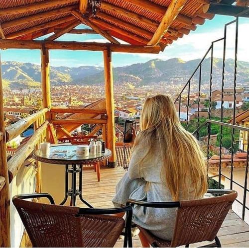 una mujer sentada en una mesa en un balcón en Cities of the World - Apartments Cusco, en Cusco