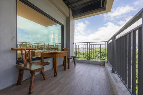 a balcony with a table and benches and a large window at 里夏民宿.墾丁後壁湖 in Hengchun