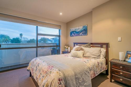 a bedroom with a bed and a large window at Waterways Serenity in Whitianga