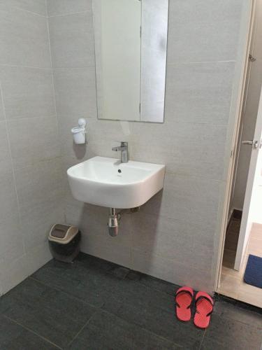 a bathroom with a sink and a mirror and two slippers at BR Troika Homestay in Kota Bharu