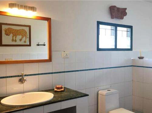 a bathroom with a sink and a toilet and a mirror at Villa Jacaranda in Varkala