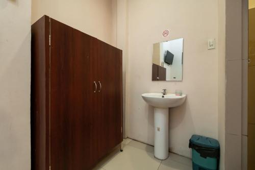 a bathroom with a sink and a wooden door at RedDoorz At Fella Homestay Medan in Medan