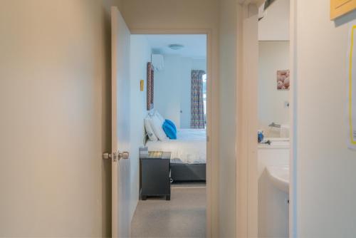a bedroom with a bed and a bathroom with a sink at Waterfront Apartments Whitianga in Whitianga