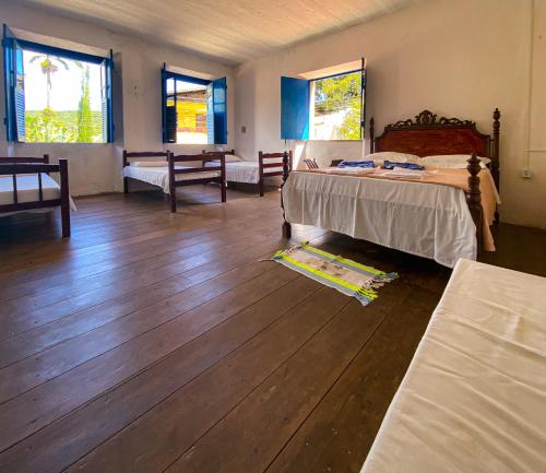 een slaapkamer met een bed en houten vloeren en ramen bij Casarão dos Uchoa in Guaramiranga