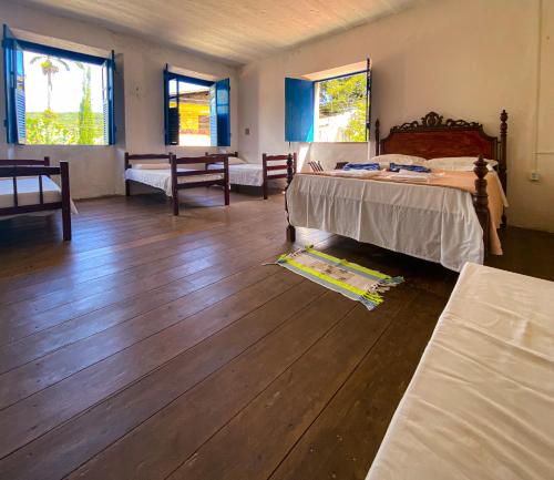 a bedroom with a bed and wooden floors and windows at Casarão dos Uchoa in Guaramiranga