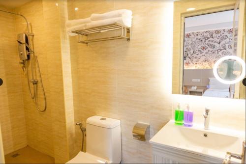 bagno con servizi igienici, lavandino e specchio di THE CROWN HOTEL @ KLIA a Sepang