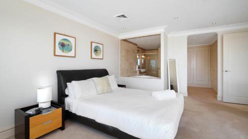 a white bedroom with a bed and a mirror at Unit 13 - 3 Bedroom Ocean View in Terrigal