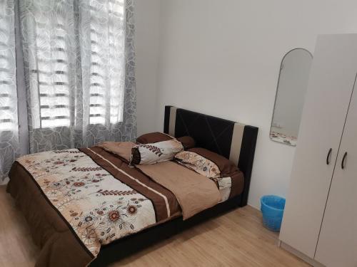 ein Schlafzimmer mit einem Bett und einem Fenster mit einem Vorhang in der Unterkunft Mahren Homestay - Homestay Merlimau Serkam Melaka 