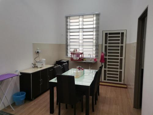 uma cozinha com mesa e cadeiras e uma janela em Mahren Homestay - Homestay Merlimau Serkam Melaka 