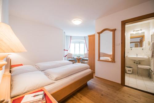 Un dormitorio con una cama, un lavabo y un espejo. en Residence Villa Maria, en Sesto