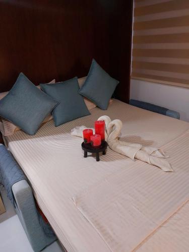 a bed with two red candles and a towel on it at City View at The Persimmon Studios in Cebu City