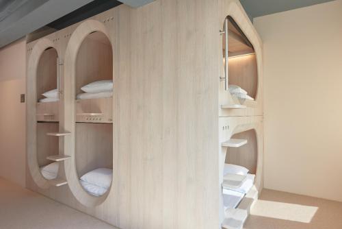 a room with a wooden wall with circular shelves at KINN Capsule in Singapore