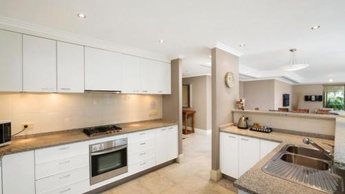 uma cozinha com armários brancos e um lavatório em Unit 40 - 4 Bed Part Ocean View em Terrigal