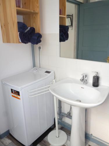 ein weißes Badezimmer mit Waschbecken und Spiegel in der Unterkunft Skipper Appartement à Sangatte au premier étage à 50 metres de la plage in Sangatte