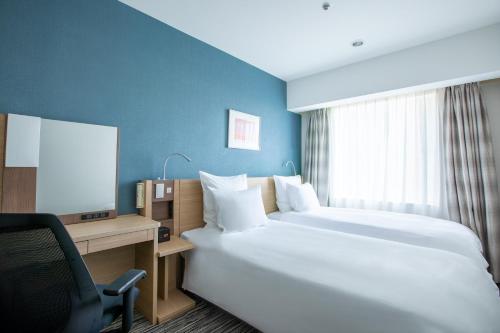 Cette chambre comprend deux lits, un bureau et une chaise. dans l'établissement ANA Crowne Plaza Hiroshima, an IHG Hotel, à Hiroshima