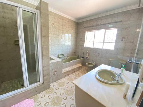 a bathroom with a sink and a shower and a tub at CHIC Guest House & Solar system accommodations in Germiston