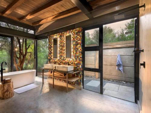 uma casa de banho com uma banheira, um lavatório e janelas em Mbazo Safaris em Pilanesberg