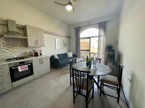 a kitchen and a dining room with a table and a couch at Seafront Apartment with Balcony Overlooking Marina in Għajnsielem