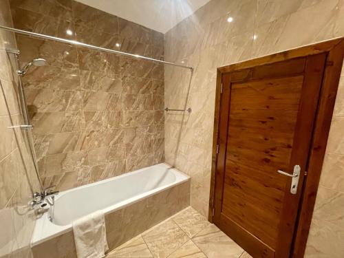 a bathroom with a tub and a shower with a door at Seafront Apartment with Balcony Overlooking Marina in Għajnsielem