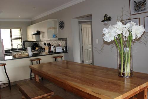 a kitchen with a wooden table with a vase of flowers at Sunbird Haven Self-Catering Sleeps 8 in Clarens