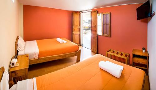 a small room with two beds and a television at Le Foyer Arequipa in Arequipa