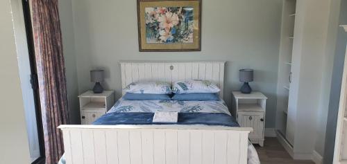 een slaapkamer met een wit bed met blauwe kussens bij Modern Solar powered 1 bed studio apartment with amazing views in Plettenbergbaai