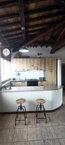 a kitchen with two stools in front of a counter at Il cielo in una stanza in Foligno