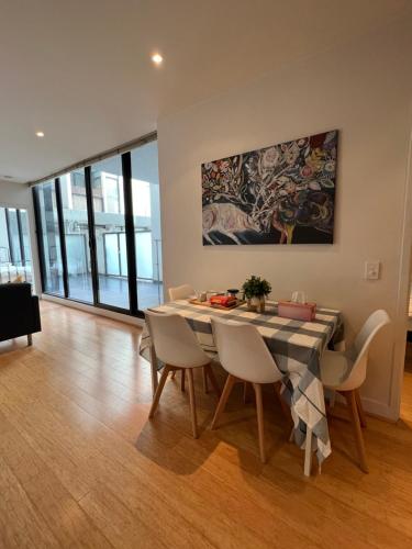 a dining room with a table and chairs and a painting at Beachside Sunshine Lifestyle-great price-entire aprt at Port Melbourne in Melbourne