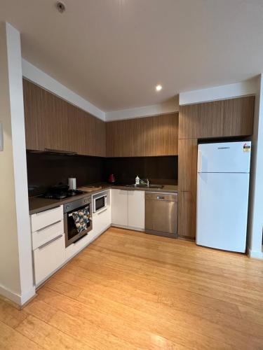 a kitchen with a white refrigerator and wooden cabinets at Beachside Sunshine Lifestyle-great price-entire aprt at Port Melbourne in Melbourne
