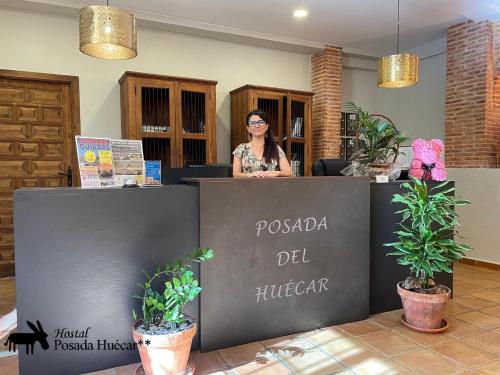 a woman standing behind a counter in a store at Hostal Posada Huecar in Cuenca