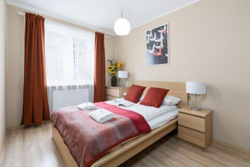 een slaapkamer met een bed met rode kussens en een raam bij Czarnieckiego Apartment with Balcony Poznań by Renters in Poznań
