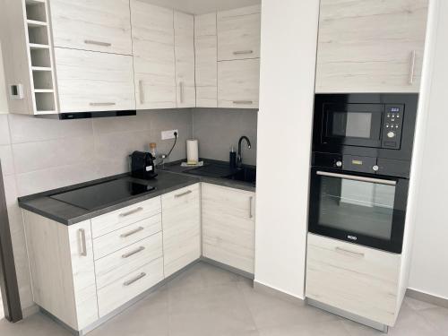 a kitchen with white cabinets and black appliances at Csatári Ház - Szekszárd in Szekszárd