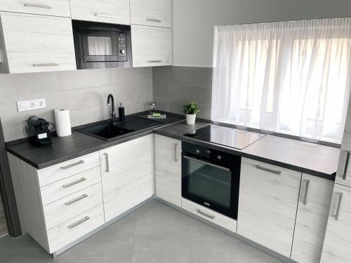 a kitchen with white cabinets and a sink and a microwave at Csatári Ház - Szekszárd in Szekszárd