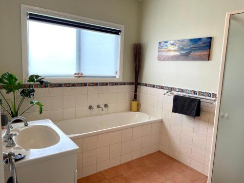 baño con bañera, lavabo y ventana en Yorks View, en Kingscote