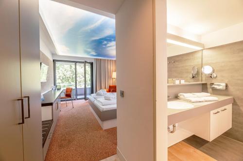 a bathroom with a sink and a bed in a room at Thermenhotel Gesundheits-Bad Buchau in Bad Buchau