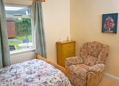 a bedroom with a chair and a chair and a window at Garden Holiday Cottage by Trident Holiday Homes in Clogheen