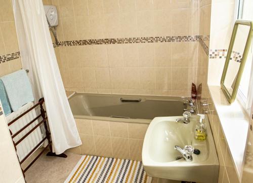 a bathroom with a sink and a bath tub at Garden Holiday Cottage by Trident Holiday Homes in Clogheen
