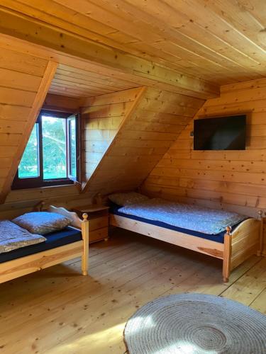 a room with two beds in a log cabin at Domek nad jeziorem Winiec in Miłomłyn