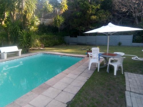 a pool with an umbrella and a table and chairs at M AND M HOME FROM HOME in Port Edward