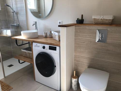 een badkamer met een wasmachine en een wastafel bij Maison au cœur de la La Palmyre in Les Mathes