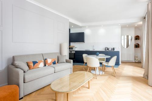 un salon avec un canapé et une table dans l'établissement Reva Suites, à Paris