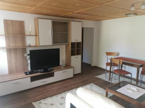 un salon avec une télévision, un canapé et une table dans l'établissement Haus am Bach, à Kirchberg in Tirol