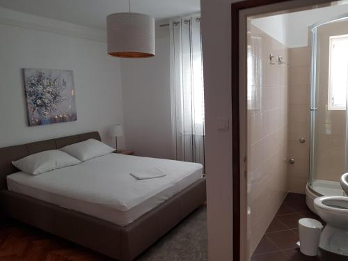 een slaapkamer met een bed en een badkamer met een toilet bij Apartments Antica in Rab