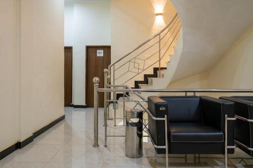 a lobby with a staircase and black chairs at RedDoorz Plus near Ramayana Pematangsiantar in Pematangsiantar