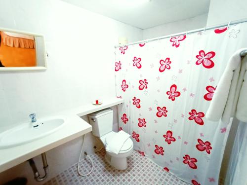 a bathroom with a toilet and a shower curtain with flowers at Chiang Mai Lodge in Chiang Mai