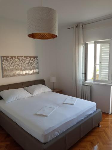 een slaapkamer met een groot wit bed en een raam bij Apartments Antica in Rab